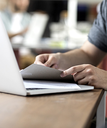 Hands turning pages with a laptop